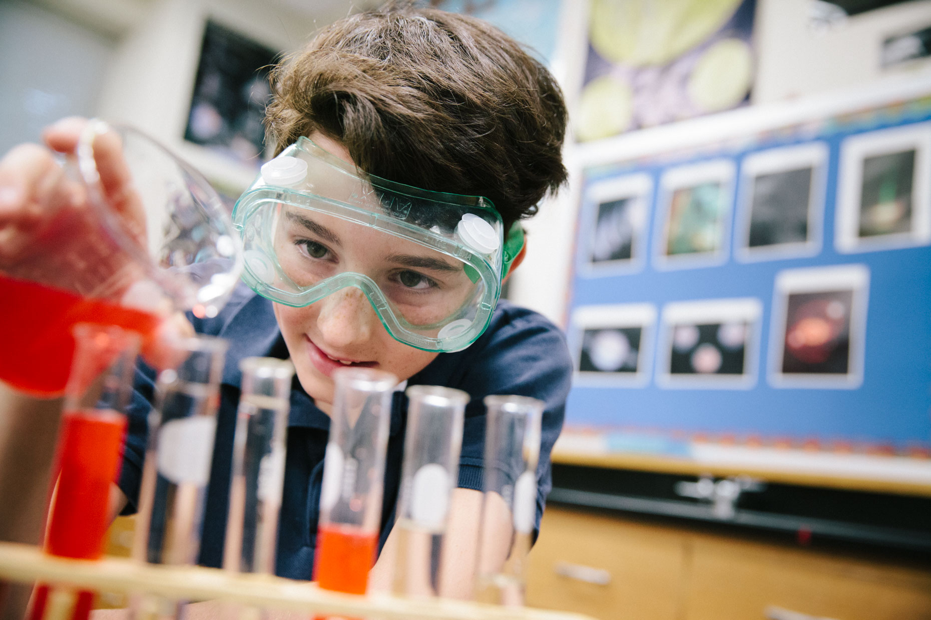 Boy doing science experiment in lab with safety goggles.