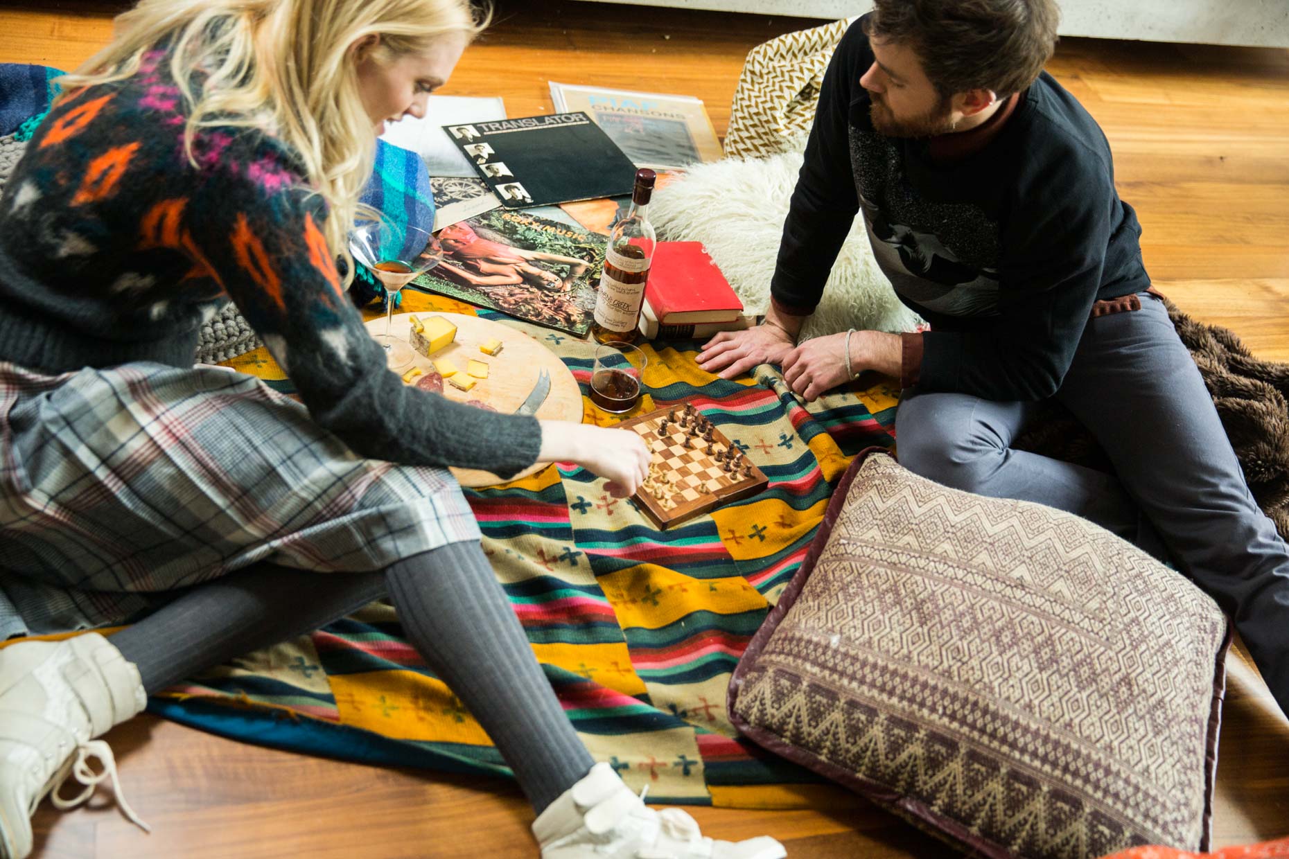 Man and women playing card game on colorful blanket