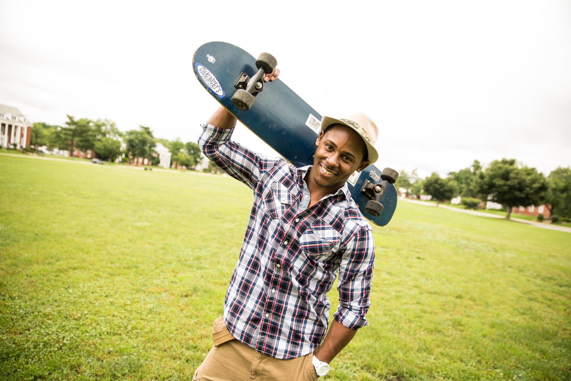 African American man wearing a hat and carrying a skateboard