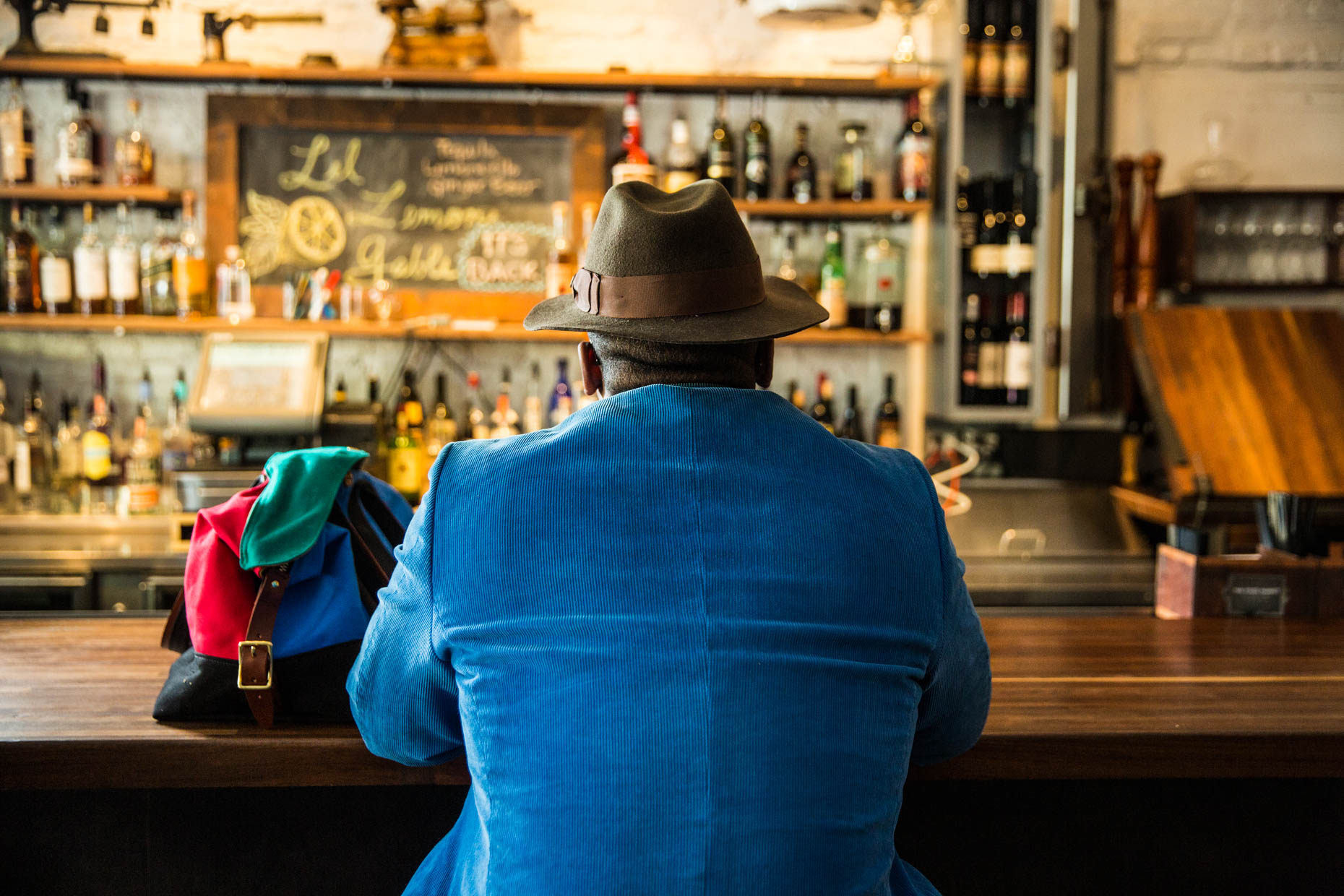 Man with hat and blue suit sitting at bar