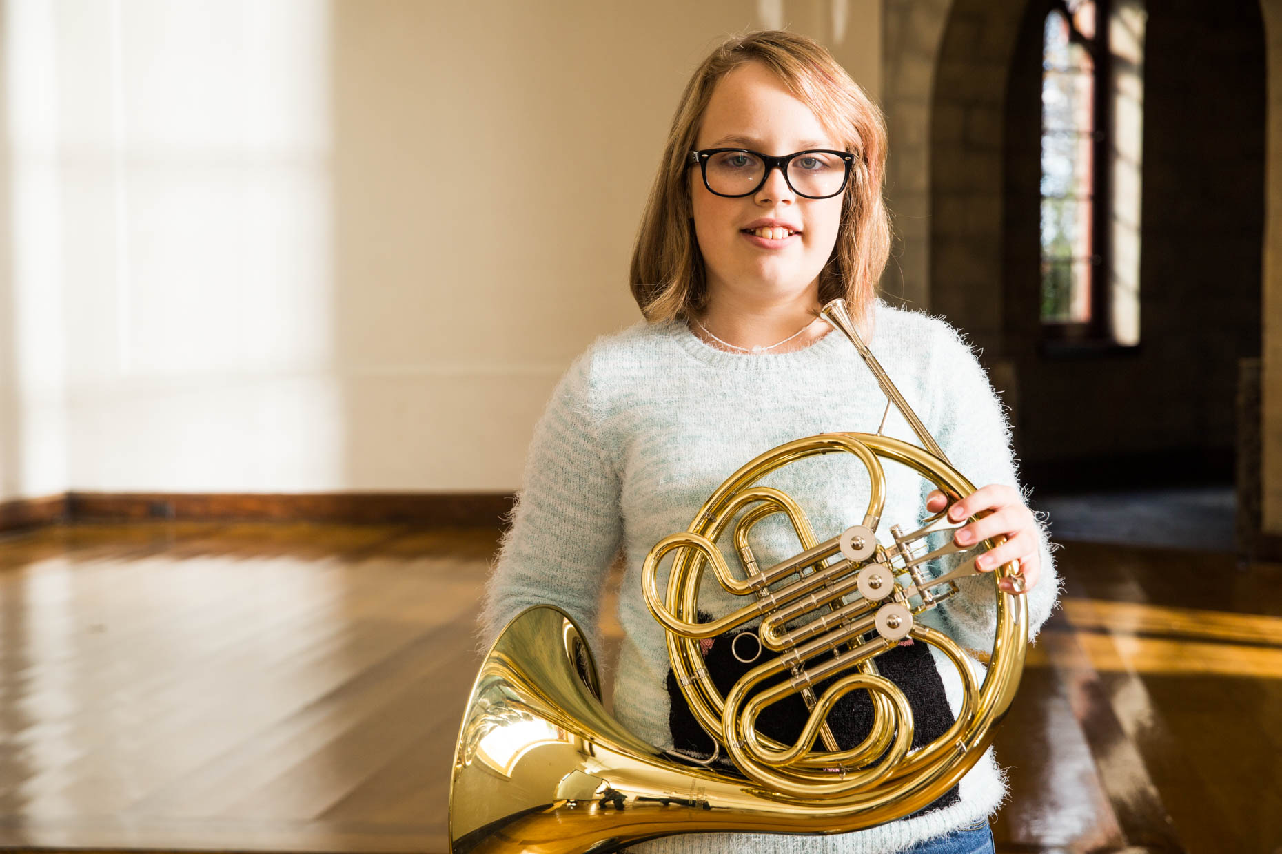 Young girl with glasses holding French Horn.