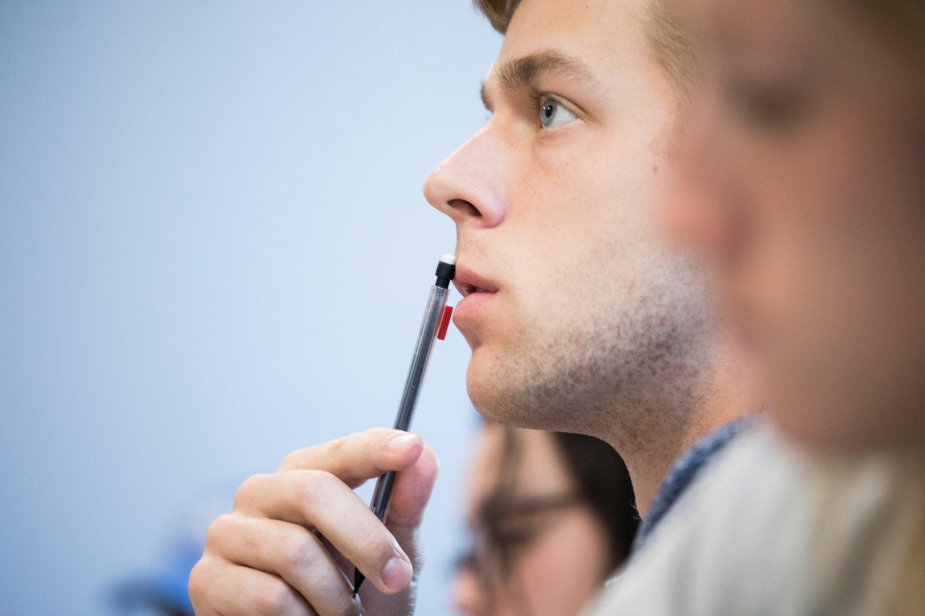 Closeup of student in class with pencil.