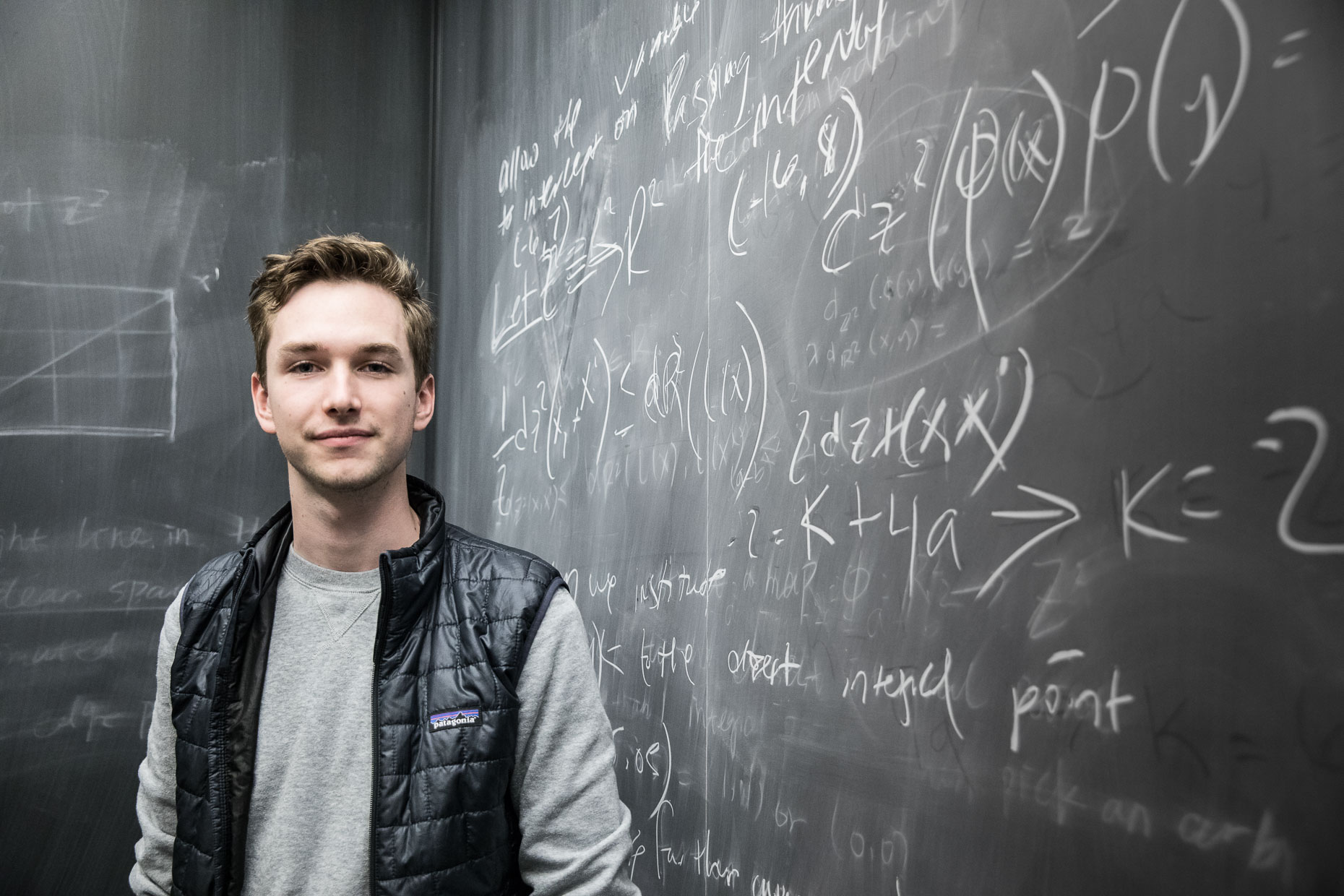 Student portrait in front of blackboard. 