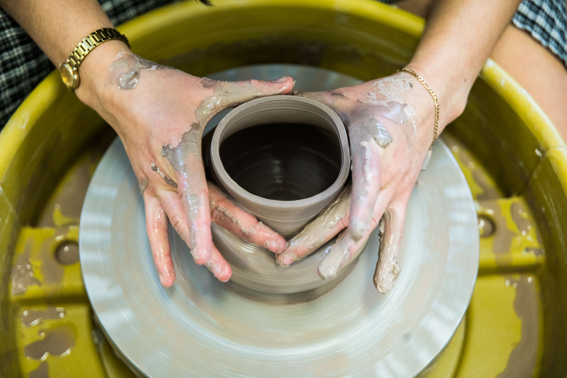 Detail of college student hands on a pottery wheel.
