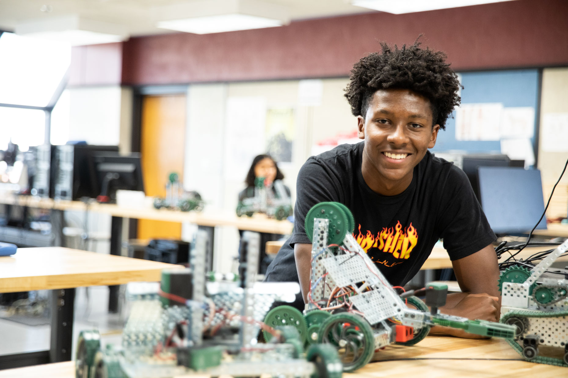 Portrait of African American student with robot in engineering lab.