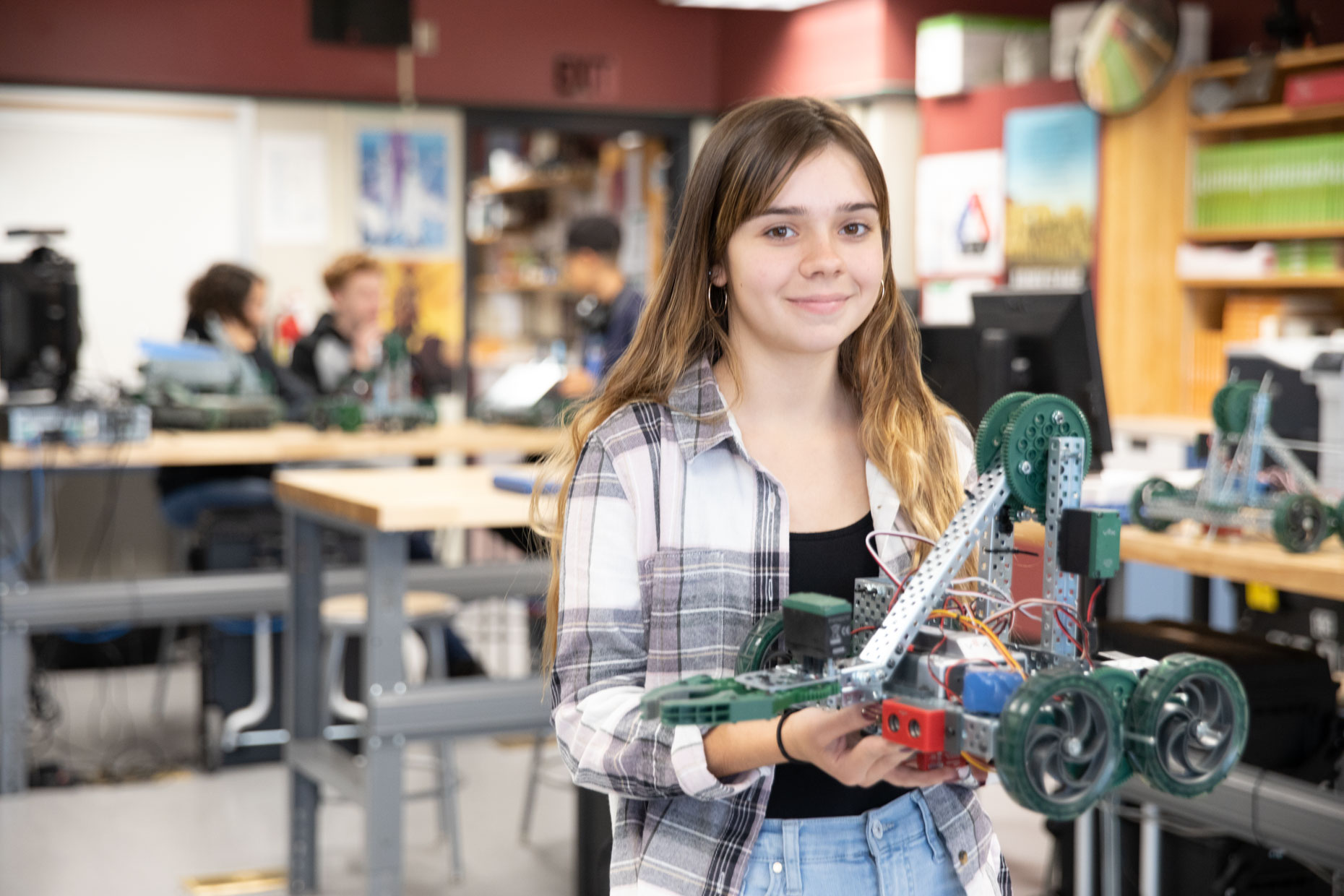 Female student with robot in engineering lab.